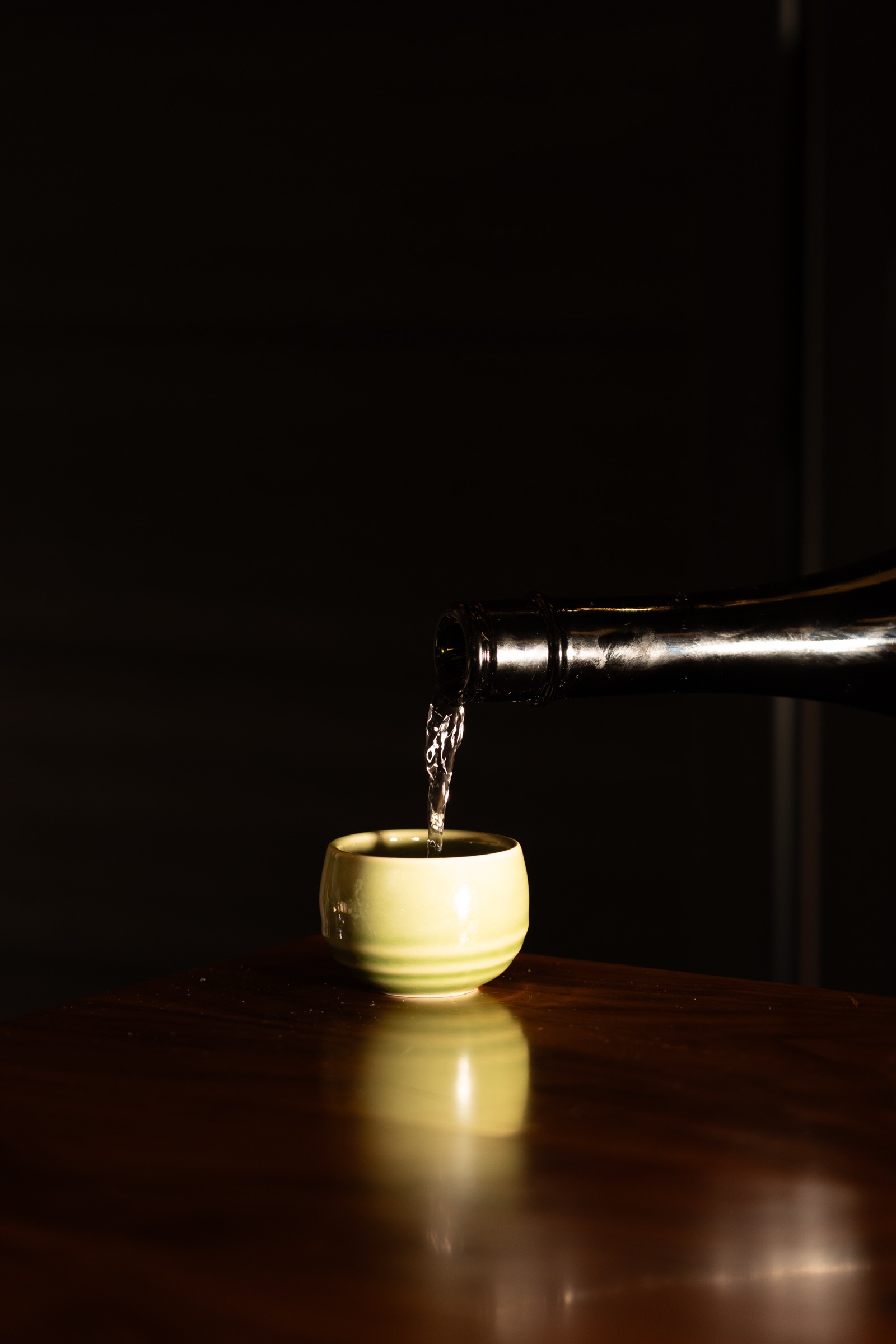 Sake being poured into a green ceramic cup